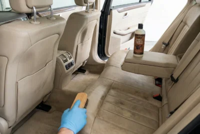 Limpiando asientos traseros de cuero beige con cepillo.