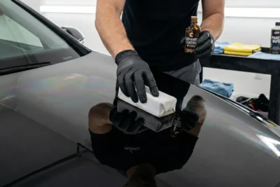 Coche deportivo con tratamiento cerámico 9H aplicado mostrando un brillo vitrificado y repelencia extrema al agua (efecto hidrofóbico) en un entorno de garaje profesional.